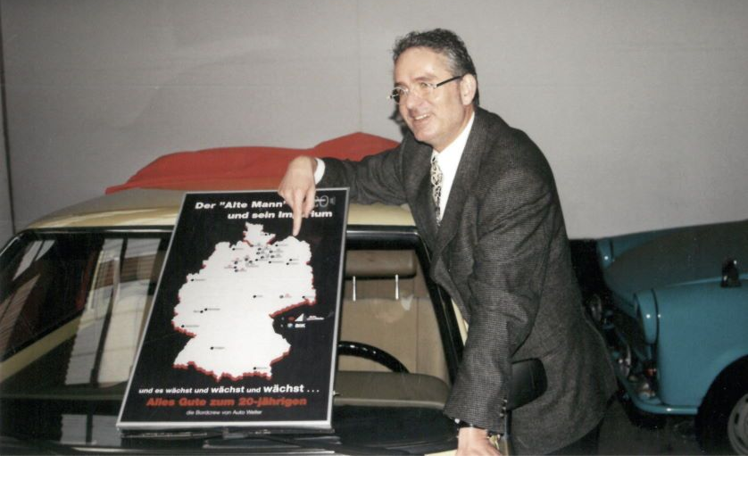 Geschäftsführer Burkhard Weller zeigt auf Deutschlandkarte mit Finger auf neue Weller-Standorte
